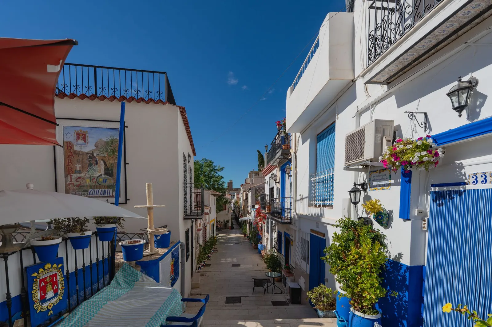 Picturesque narrow street in Alicante, Spain, with vibrant houses and clear blue skies.