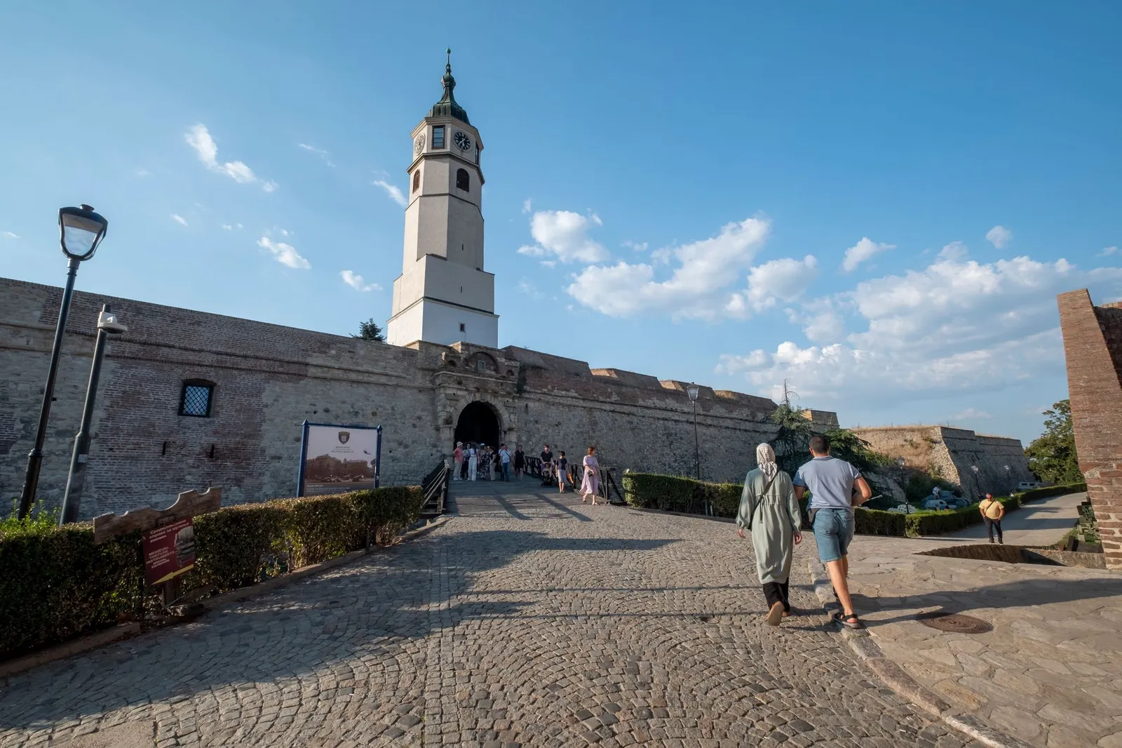 Visitors strolling through the historic Kalemegdan Fortress in Belgrade, Serbia, under a bright, clear sky.