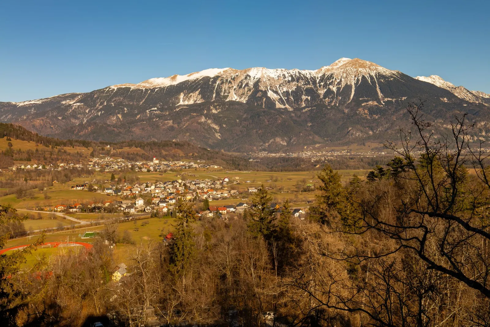 Serene landscape view of Bled, Slovenia, featuring snow-capped mountains and a quaint village.