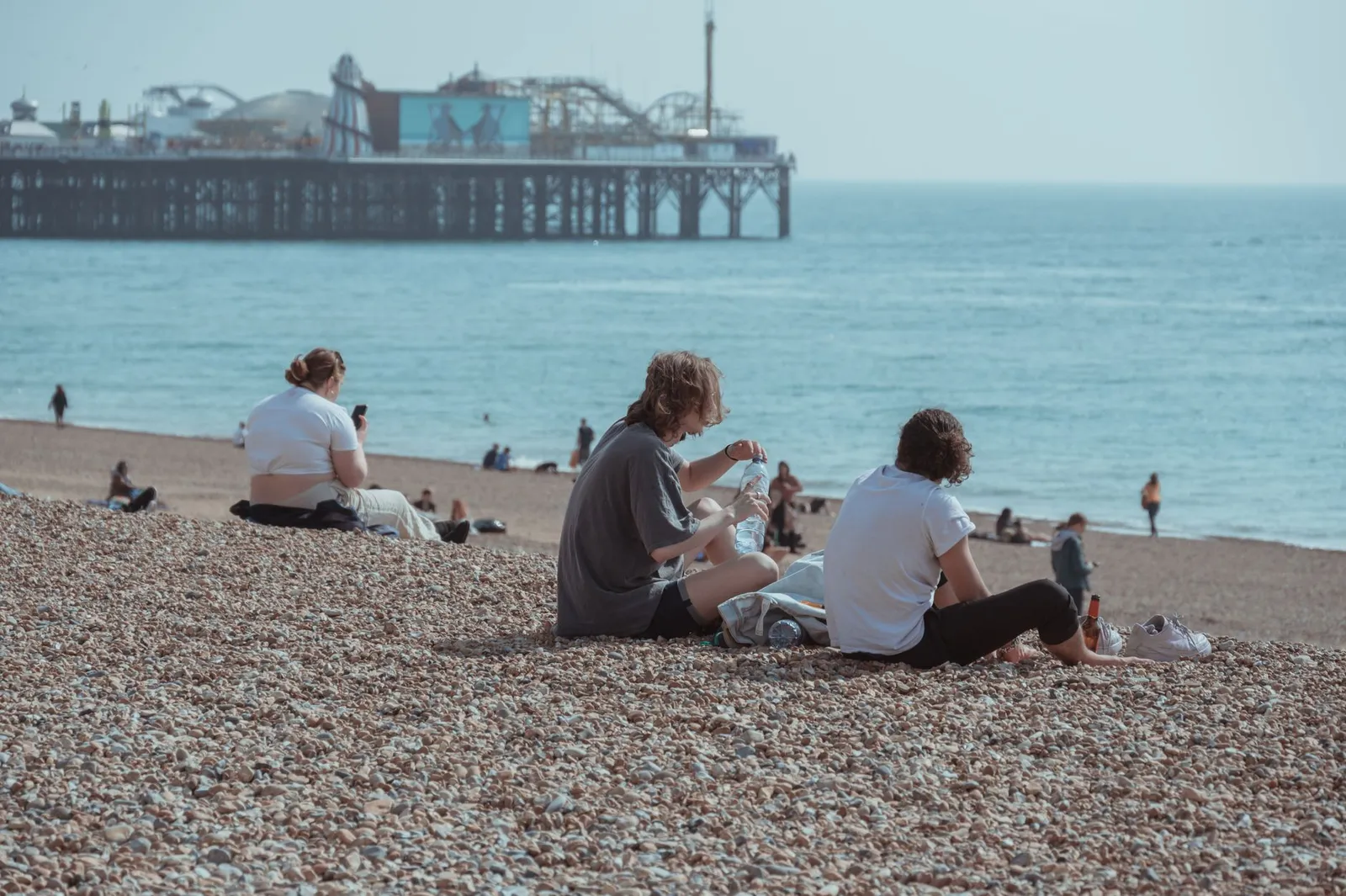 People enjoying a sunny day at Brighton Beach with the iconic pier in the background.