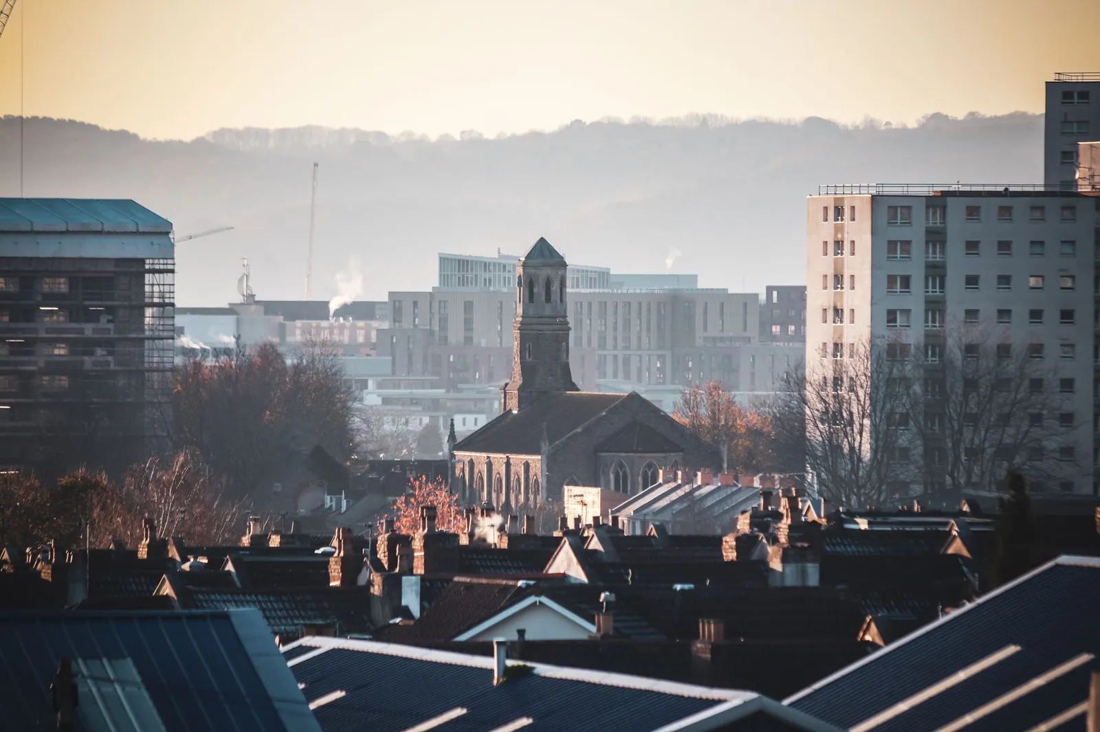 Urban view of Bristol featuring St Luke's Church amidst city buildings during a serene sunset.