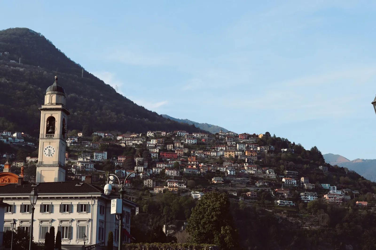 Captivating view of a bell tower against the backdrop of Como's lush hills in Lombardy, Italy.