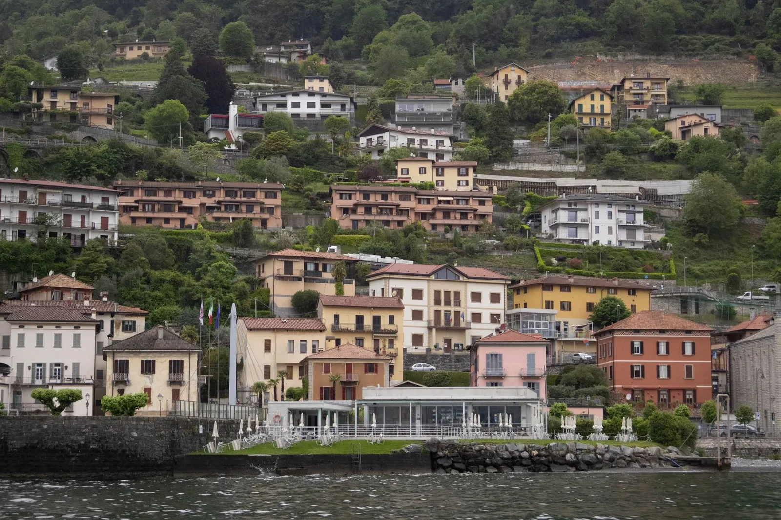 Charming hillside houses by Lake Como with lush greenery in Italy, perfect for travel enthusiasts.