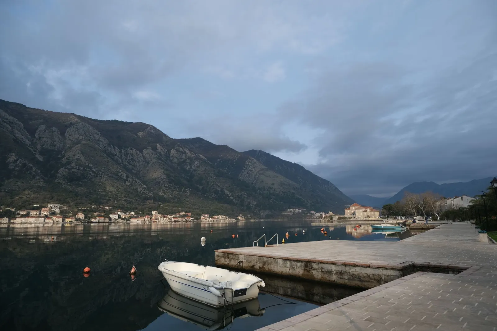 Peaceful morning view of Kotor Bay in Montenegro, showcasing calm waters and mountainous backdrop.