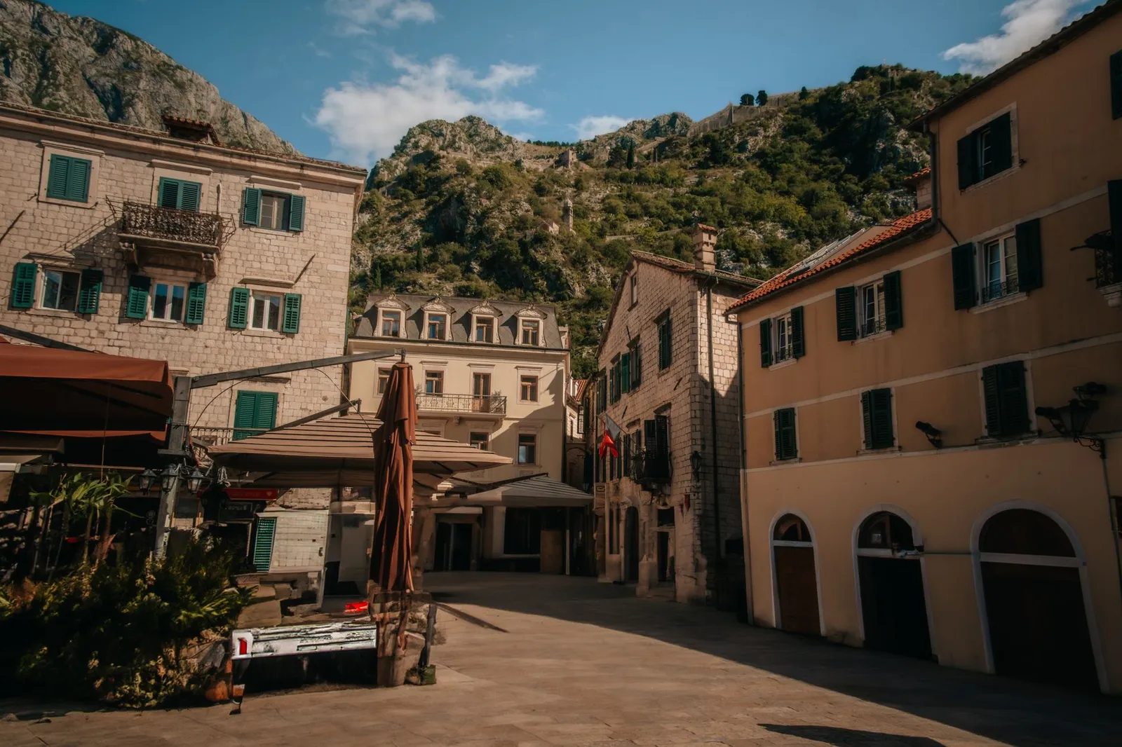 Explore a picturesque square in Kotor's Old Town, framed by mountains and historic buildings.