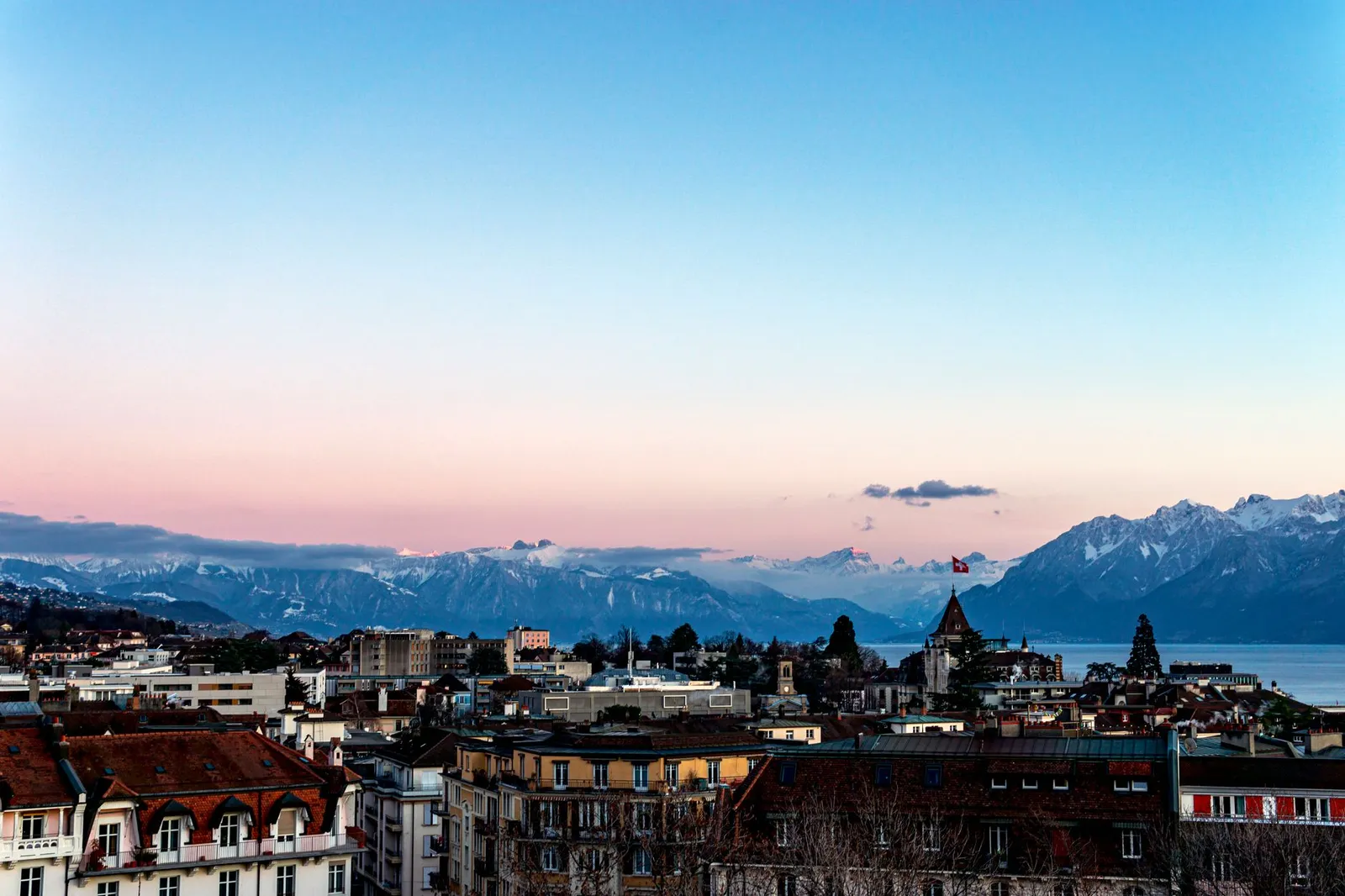 Breathtaking sunset view of Lausanne cityscape with Alps and Lake Geneva in the backdrop.