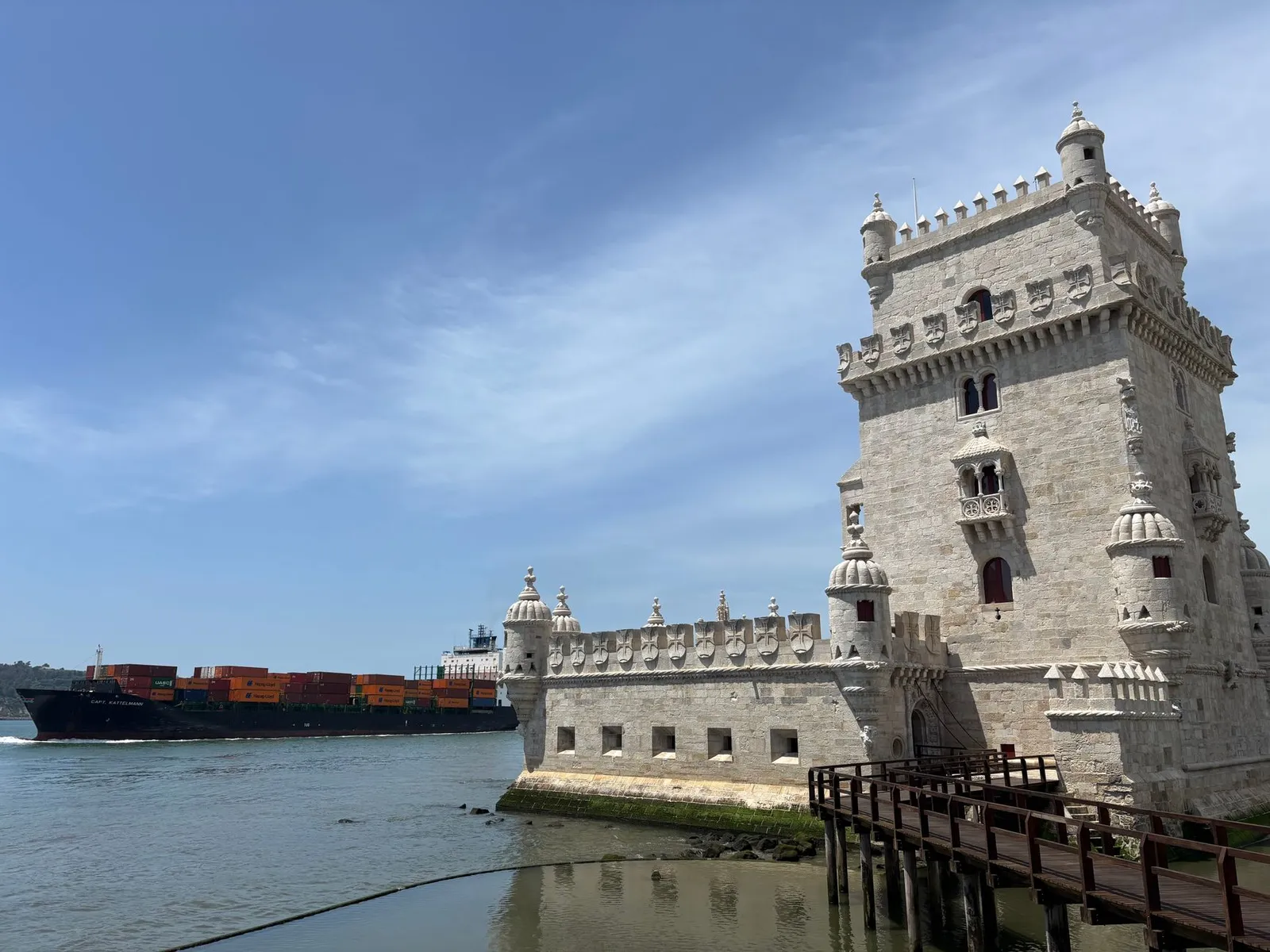 Historic Belem Tower with a container ship passing by on the Tagus River in Lisbon, Portugal.