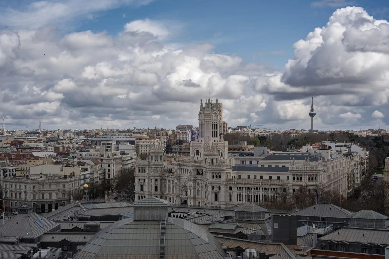 Aerial view of Madrid featuring the prominent Palacio de Cibeles under a cloudy sky.