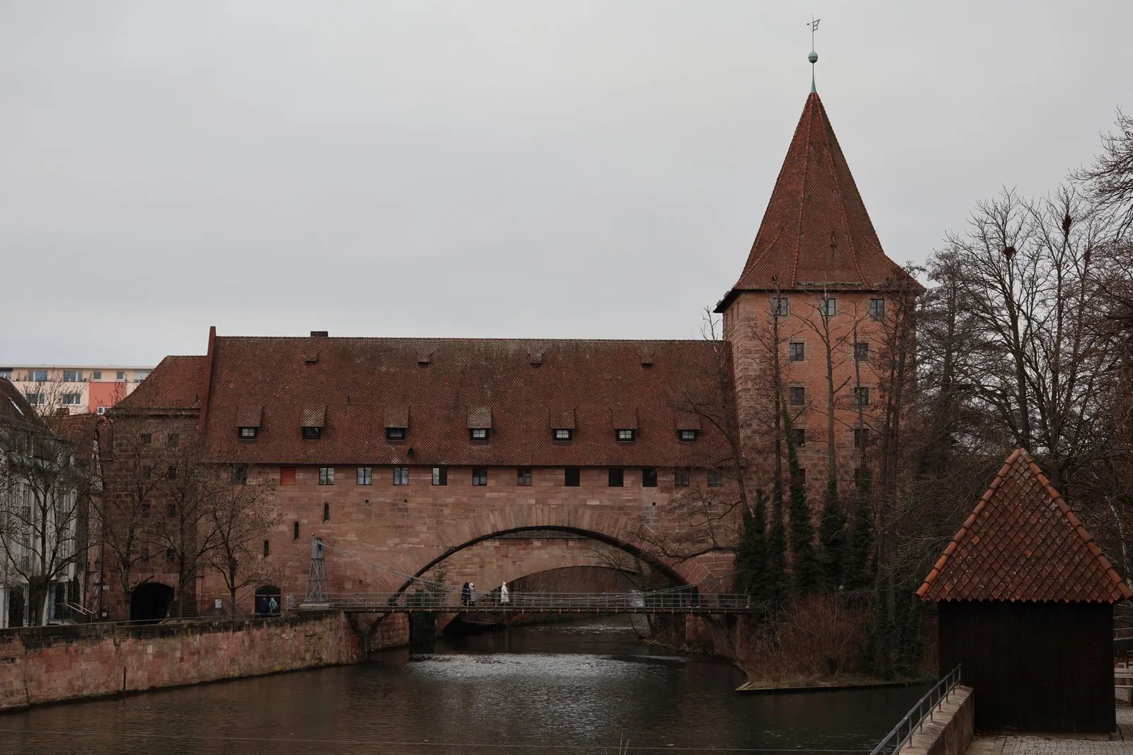 Medieval building on the Pegnitz River, Nuremberg, showcasing Gothic architecture on a cloudy day.