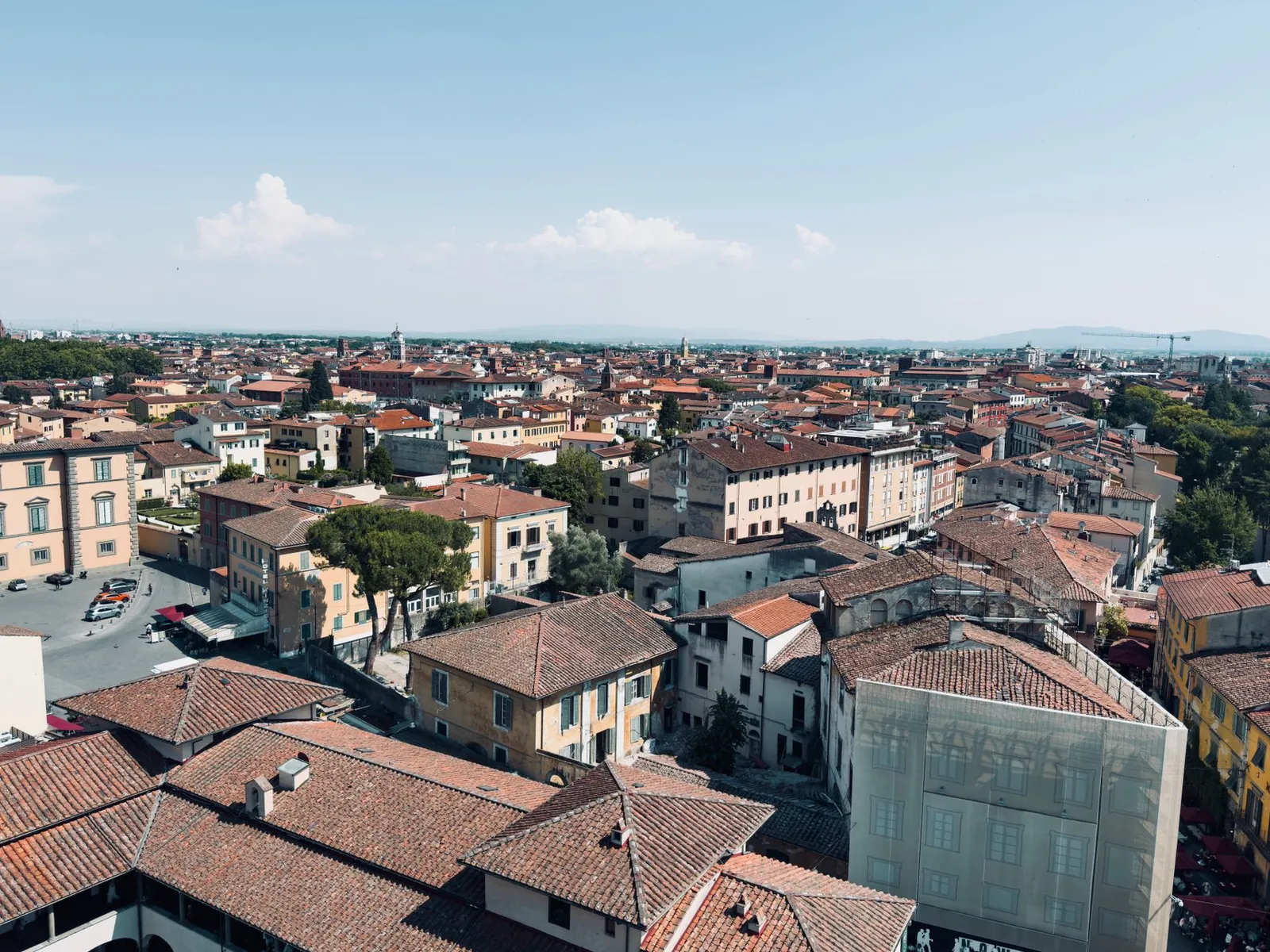Scenic aerial view of Pisa's terracotta rooftops under a clear blue sky, capturing the essence of Italian architecture.