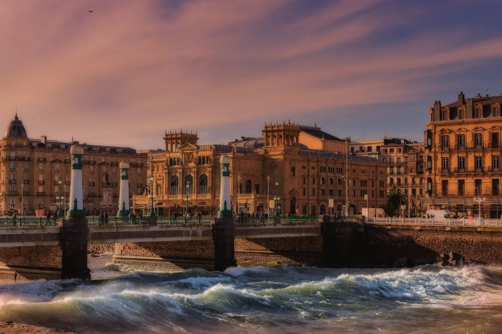 Charming view of a bridge and historic architecture in San Sebastián during sunset.
