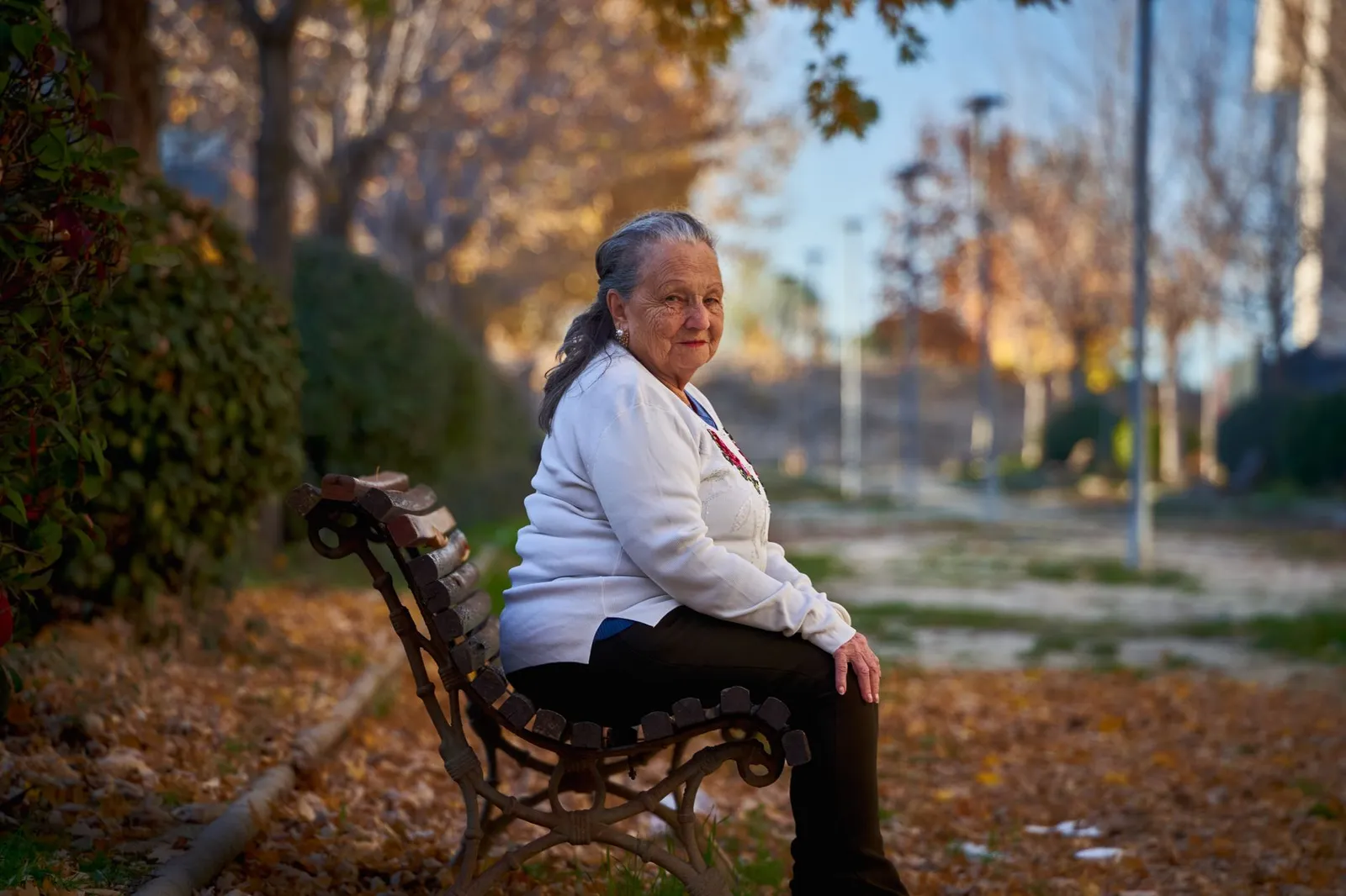 Senior woman sitting on a park bench in autumn, enjoying a tranquil moment in San Sebastián de los Reyes.