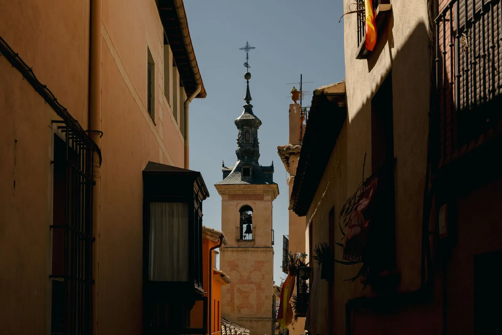 A beautiful view of the historic bell tower in Toledo, Spain, framed by traditional buildings.
