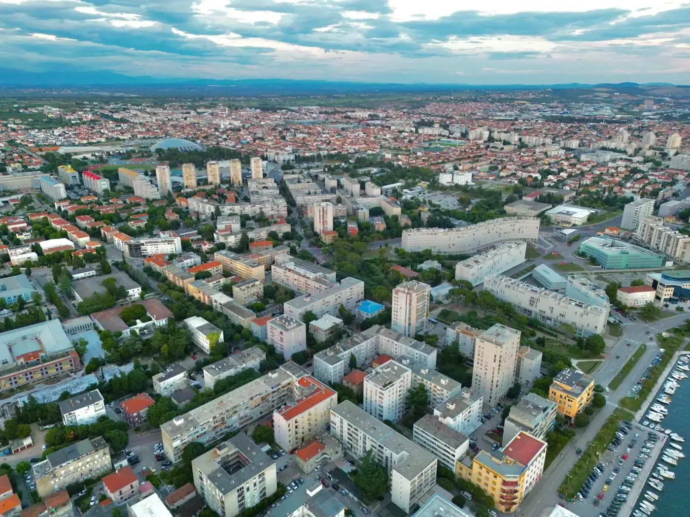 Aerial view of Zadar, Croatia, showcasing diverse architecture and vibrant city life under a serene sky.